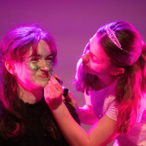 student putting lipstick on her friend